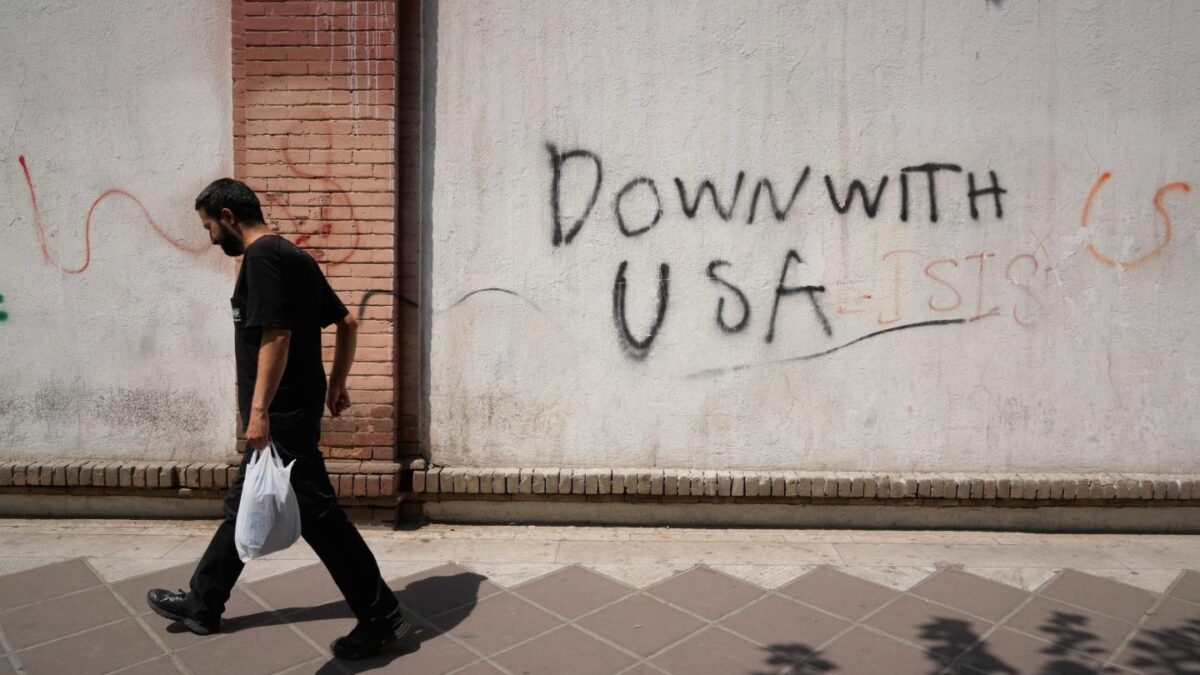 Photo of man walking past anti-U.S. graffit "Down with USA" in Tehran