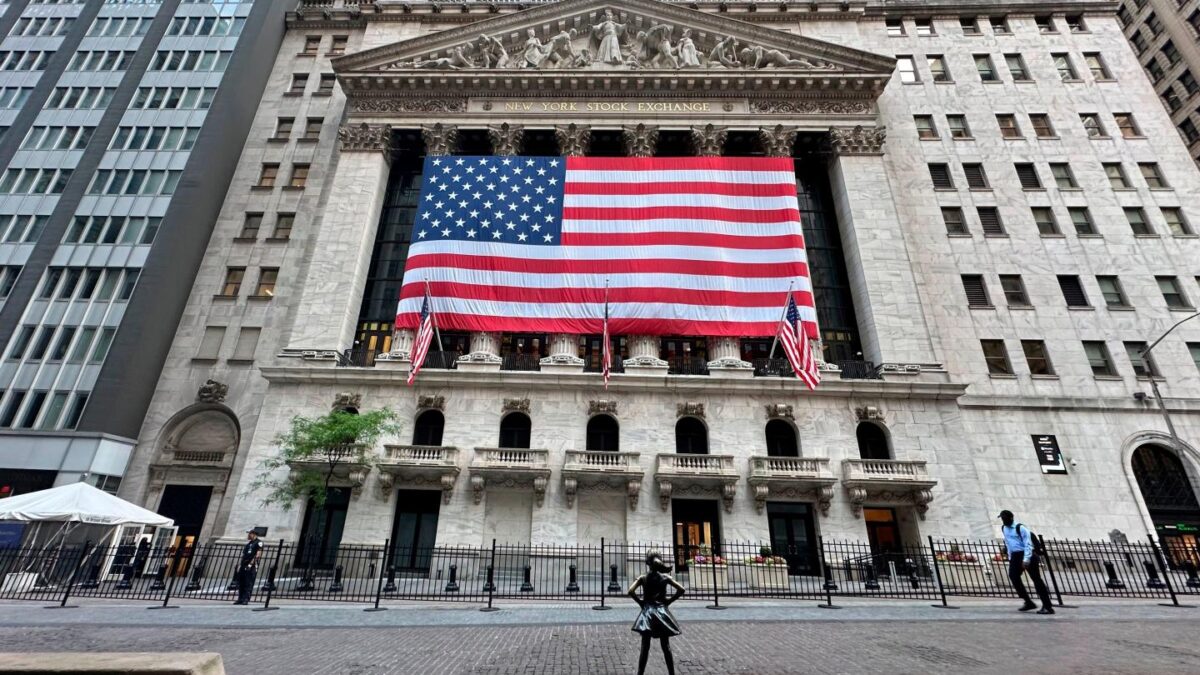 People pass the New York Stock Exchange on the street.