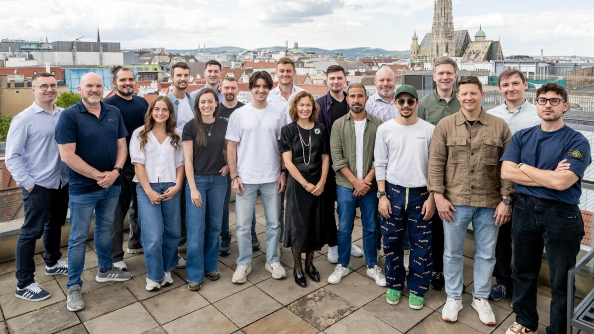 19 of Cyclops' members stand smiling at the camera from their offices in Vienna, Austria.