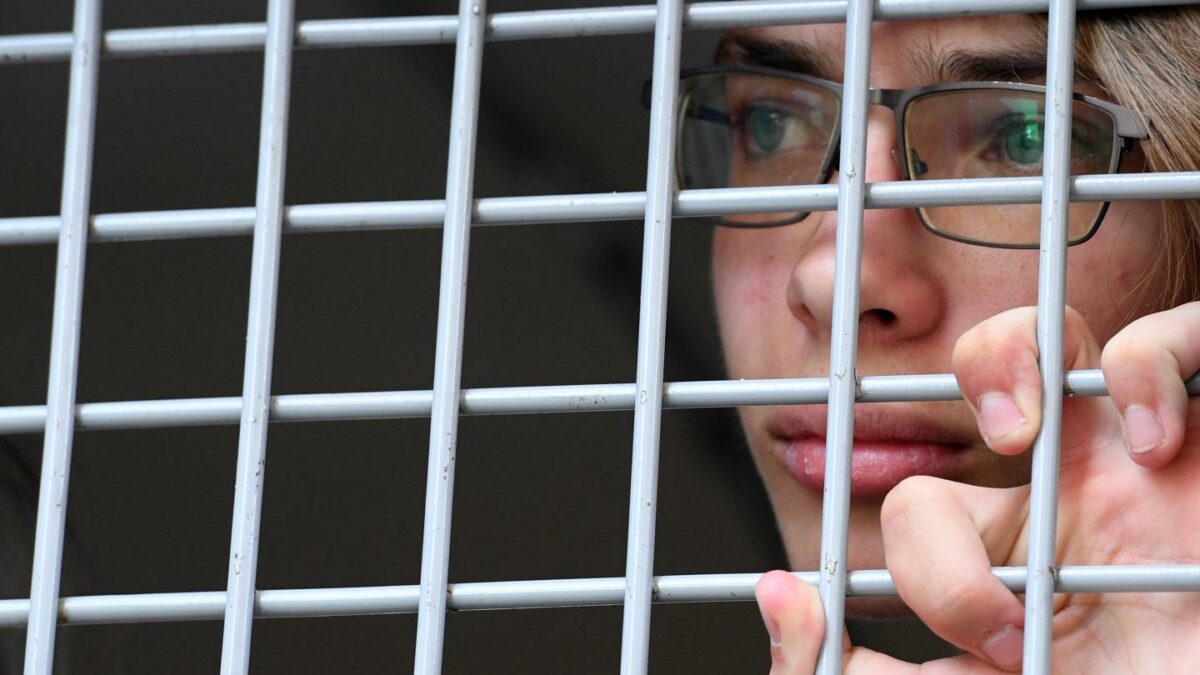 A person looking through a metal grid on a window