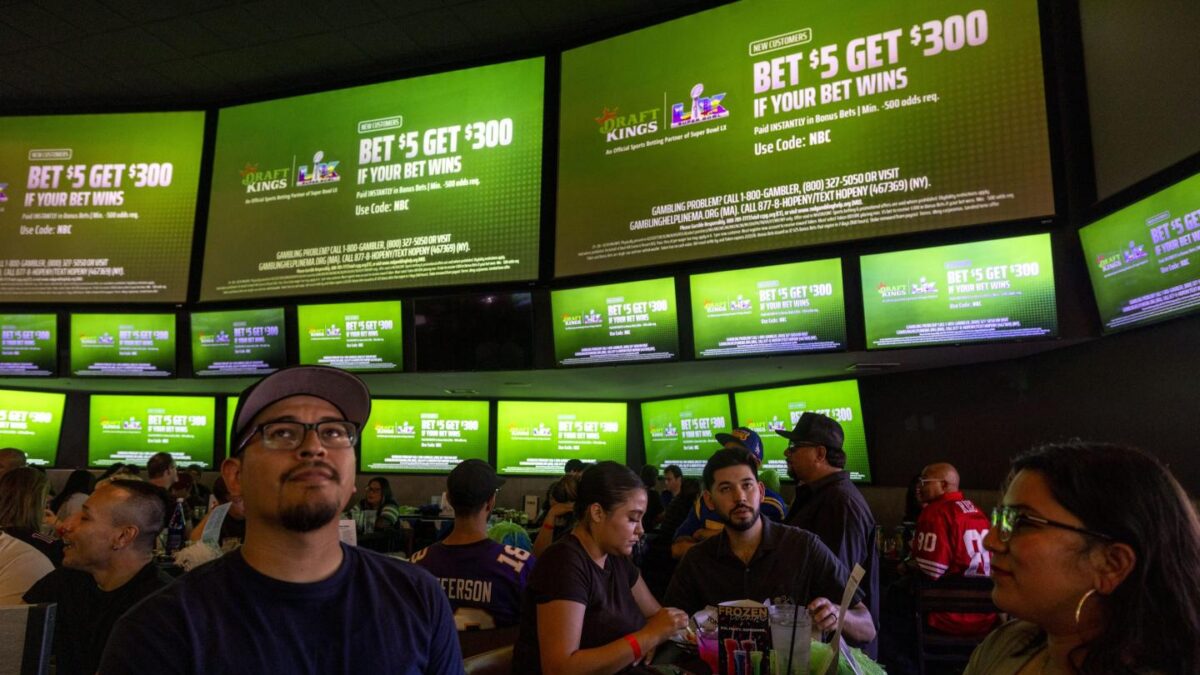 Fans Watch Super Bowl LX In California beneath tv screens with betting ads