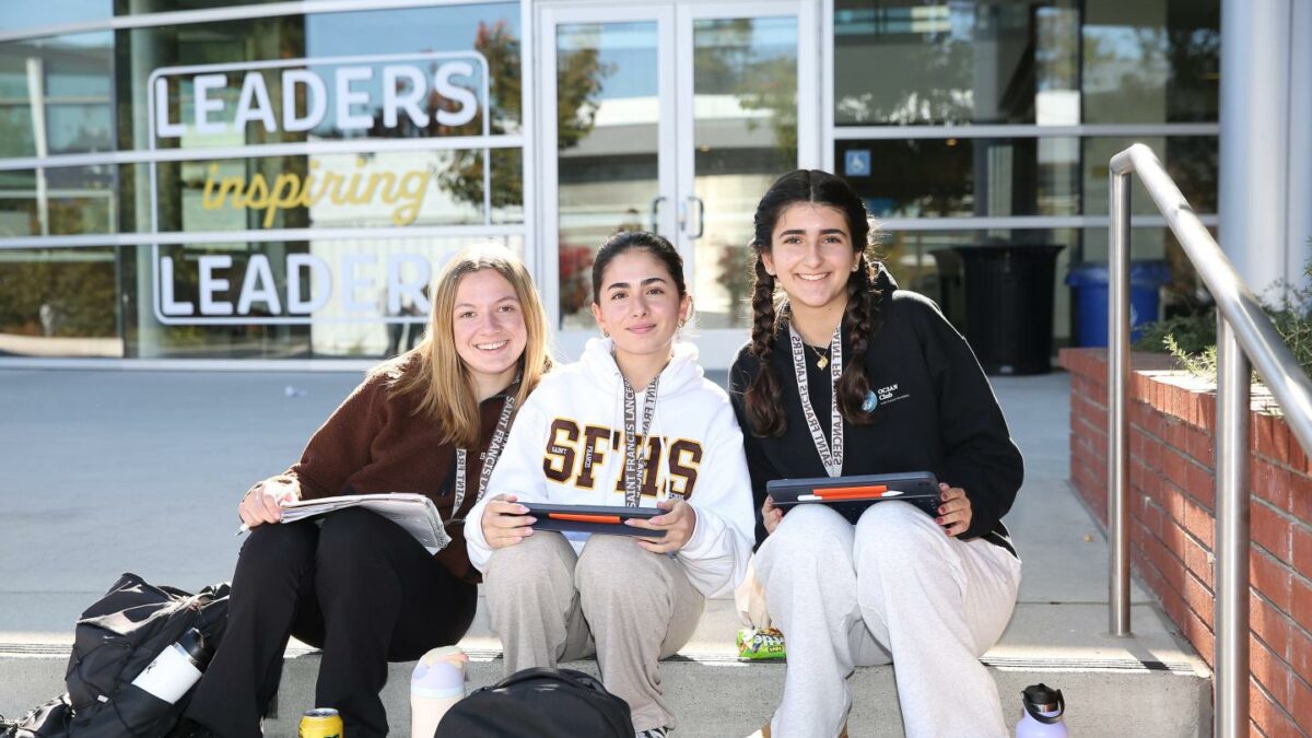 Three students posing outside of Saint Francis High School